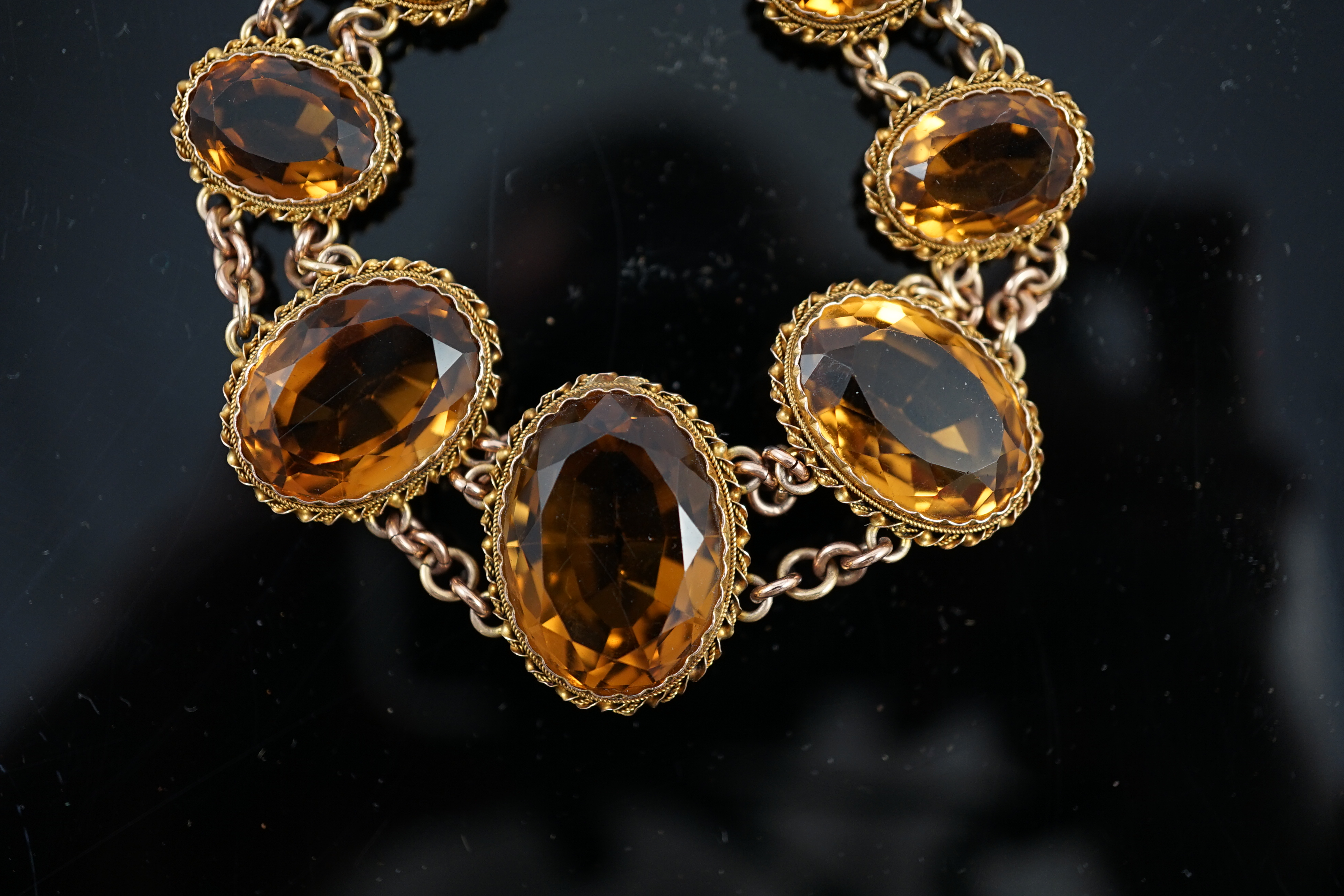 An early 20th century 9ct gold and graduated seven stone oval cut citrine set bracelet